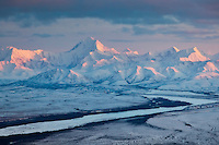 Alpenglow sunset light on the snow covered peak of Mount Hayes, 13,832 feet (4,216 m), the highest mountain in the eastern Alaska Range. View looking southwest.