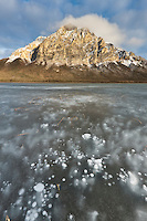 Frozen pond in the foreground of Mt Dillon of the Brooks range mountains with afternoon sun highlighting the rugged rocky face, Alaska