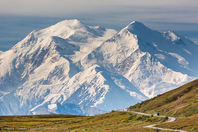 Tour bus travels the Denali Park Road through Thorofare Pass, with Mt McKinley visible along the Alaska range horizon.
