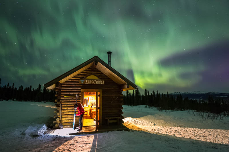 Man prepares cross country skis under the aurora in the White Mountains National Recreation Area